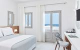 Helles und stilvolles Doppelzimmer im Costa Grand Resort & Spa – modernes Design in Weiß und Grau mit gemütlichem Bett, Arbeitsbereich und direktem Meerblick durch große Fenster.