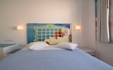 Helles Zimmer mit Doppelbett, dekorativem Fotokopfteil mit Meerblick-Motiv und mediterraner Atmosphäre – ideal für entspannte Urlaubstage.