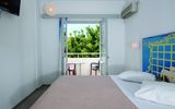 Helles Hotelzimmer mit Doppelbett, Klimaanlage und Zugang zu einem Balkon mit Sitzgelegenheit und Blick ins Grüne – ideal zum Entspannen.