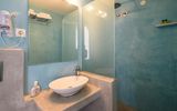 Modernes Badezimmer mit Waschbecken auf Betonplatte, großer Spiegelwand und hellblauer Duschkabine mit Regendusche.