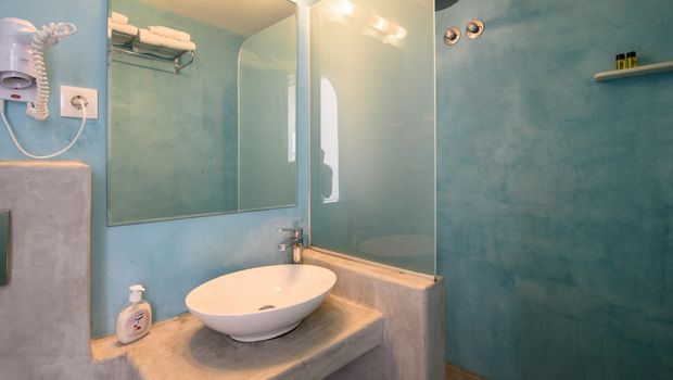 Modernes Badezimmer mit Waschbecken auf Betonplatte, großer Spiegelwand und hellblauer Duschkabine mit Regendusche.