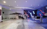 Modern gestalteter Rezeptionsbereich mit kunstvoll beleuchteter Wand in Blau-, Rot- und Weißtönen sowie stilvollen Sitzmöglichkeiten – Empfang mit kreativem Flair.