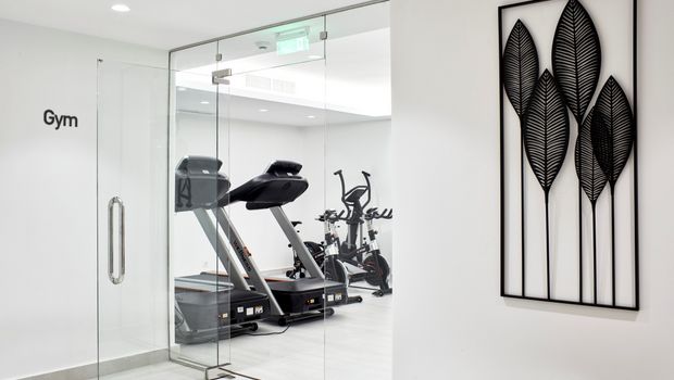 Modern ausgestatteter Fitnessraum im Costa Grand Resort & Spa mit Laufbändern und Ergometern – stilvolles, lichtdurchflutetes Ambiente mit Glaswänden und minimalistischer Dekoration.