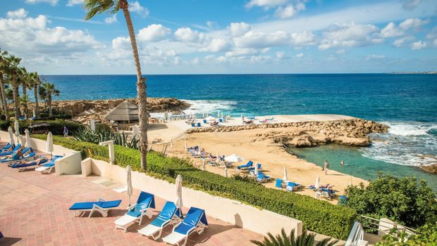 Felsige Badebucht mit Sonnenterrassen, Liegen und kristallklarem Wasser direkt am Meer.