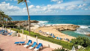 Felsige Badebucht mit Sonnenterrassen, Liegen und kristallklarem Wasser direkt am Meer.