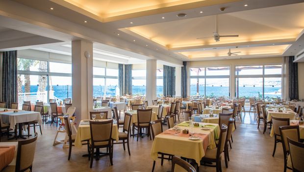 Helles Restaurant mit Meerblick, großen Panoramafenstern und freundlich gedeckten Tischen.